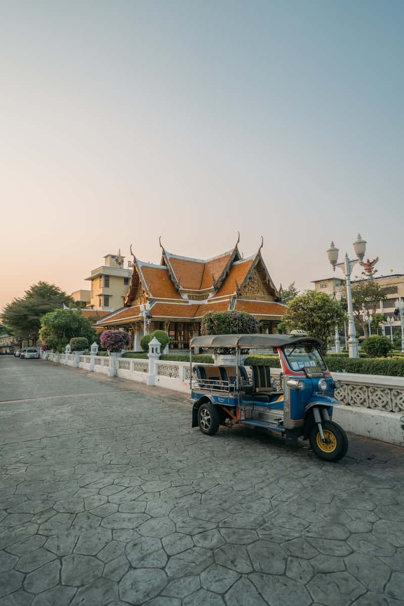 Traditional Thai architecture with a tuk tuk and blue sky.