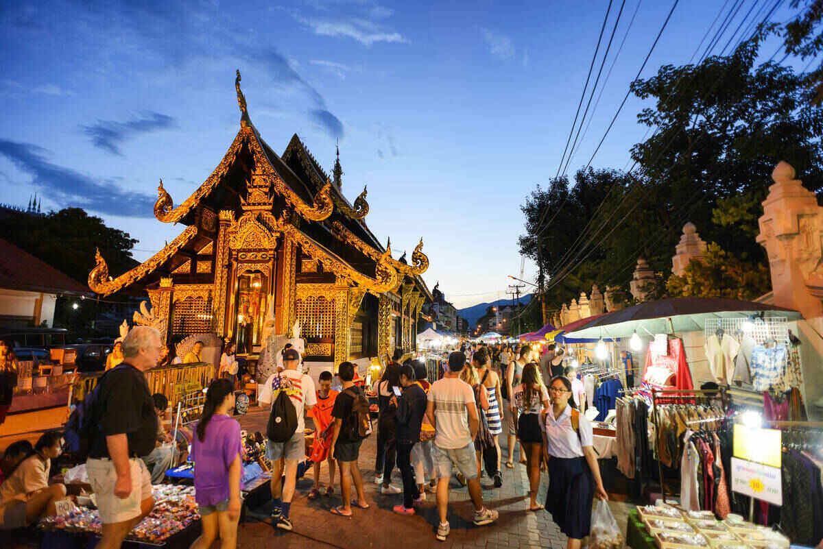 Ornate temple during twilight and a night market next to it.