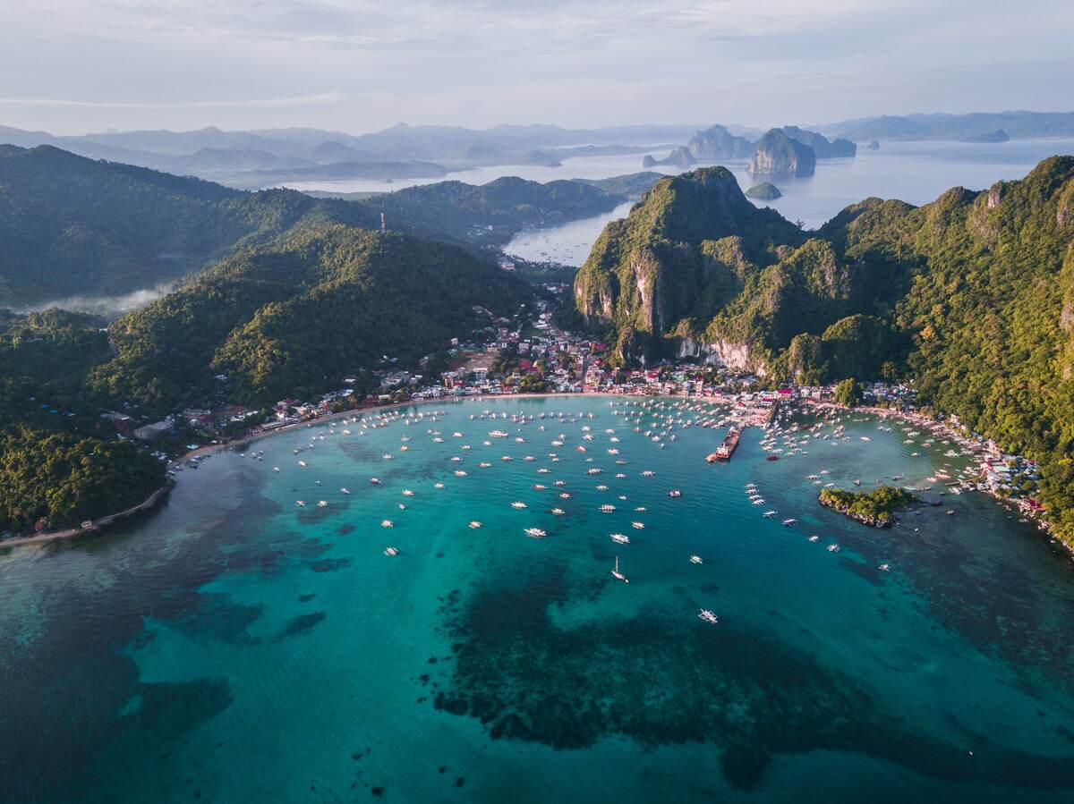 Tourist boats in a blue lagoon in El Nido Palawan.