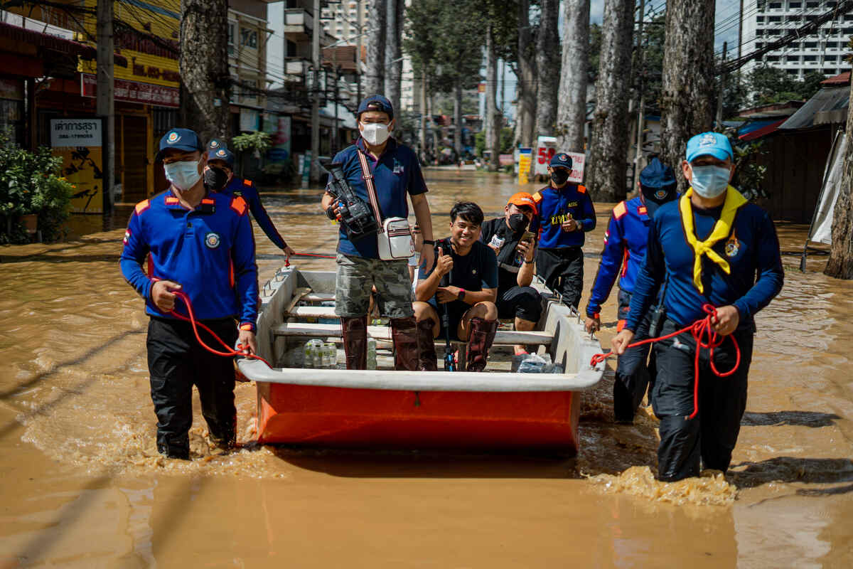 Traditional boat with people in a a flooded city in Thailand