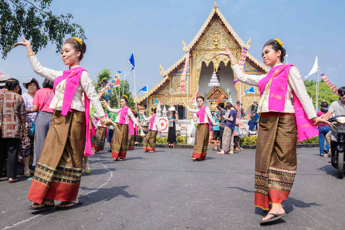 Women dancing a traditional dance near a Buddhist temple.