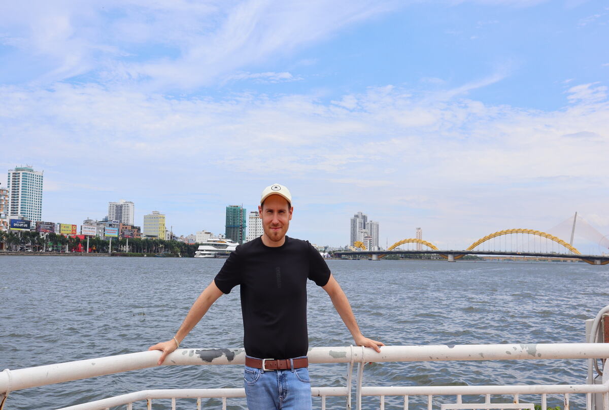 View of the Dragon Bridge in Da Nang from afar with a man posing