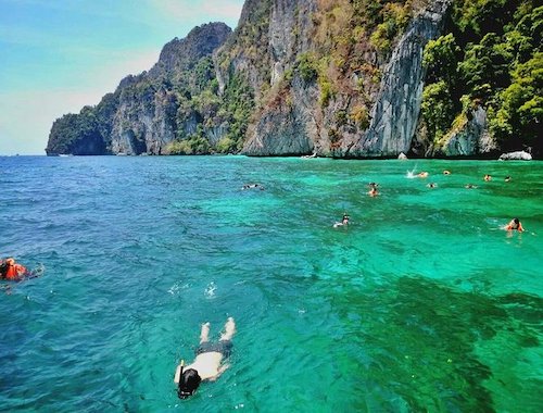 Tourists snorkeling in clear blue waters.