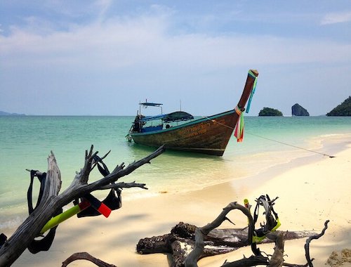 Wrecked boat on a sandy beach at sunset.