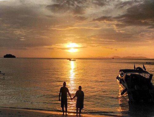 Silhouetted couple on a beach at sunset.