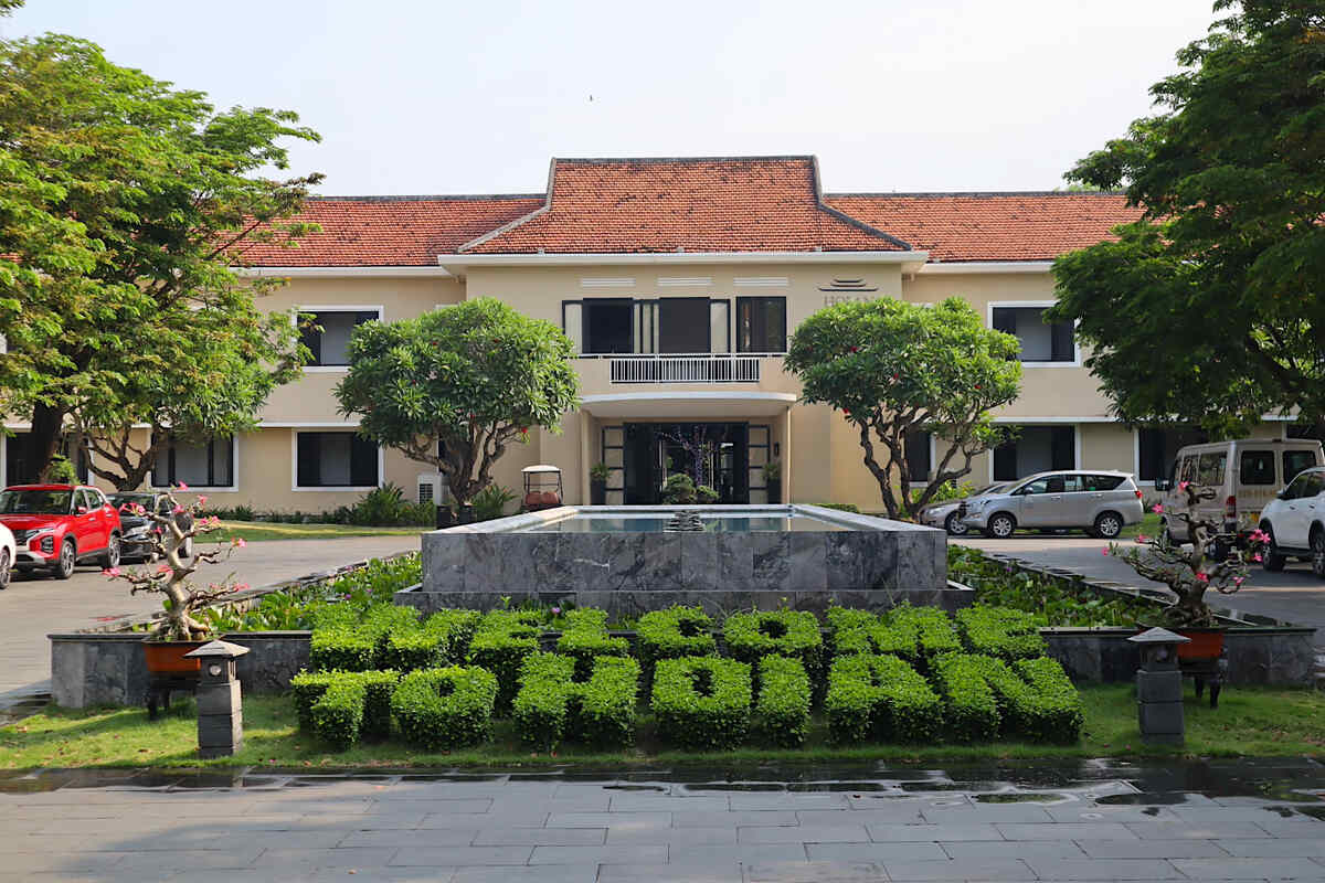 Green "HOI AN" hedge sign with architecture.