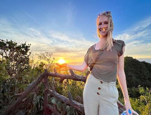 Woman holding up the sun over a mountain view.