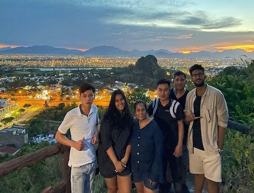 Group photo of people at dusk with city lights below.