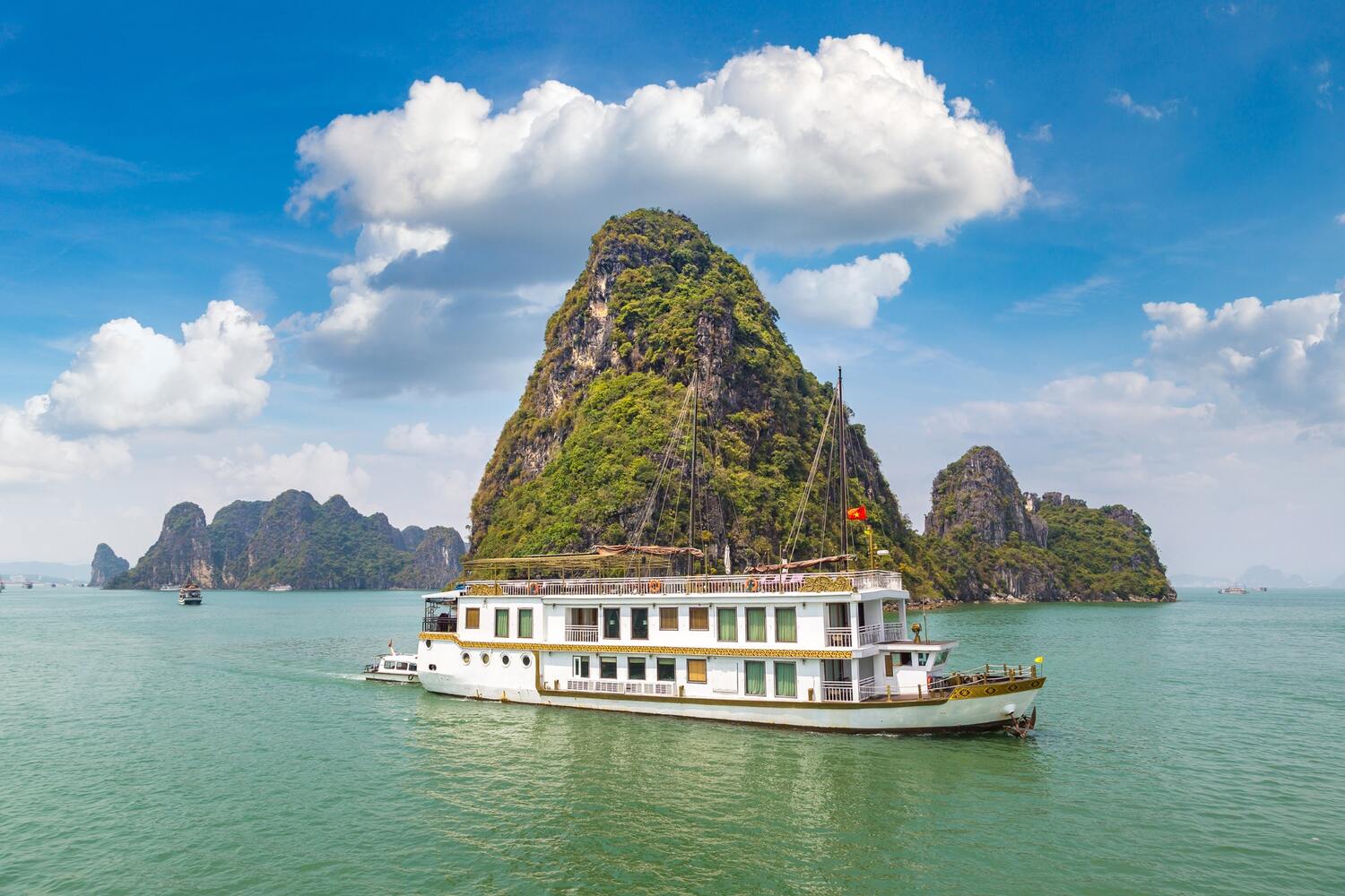 Boat cruising by a distinctive mountain on a lake.