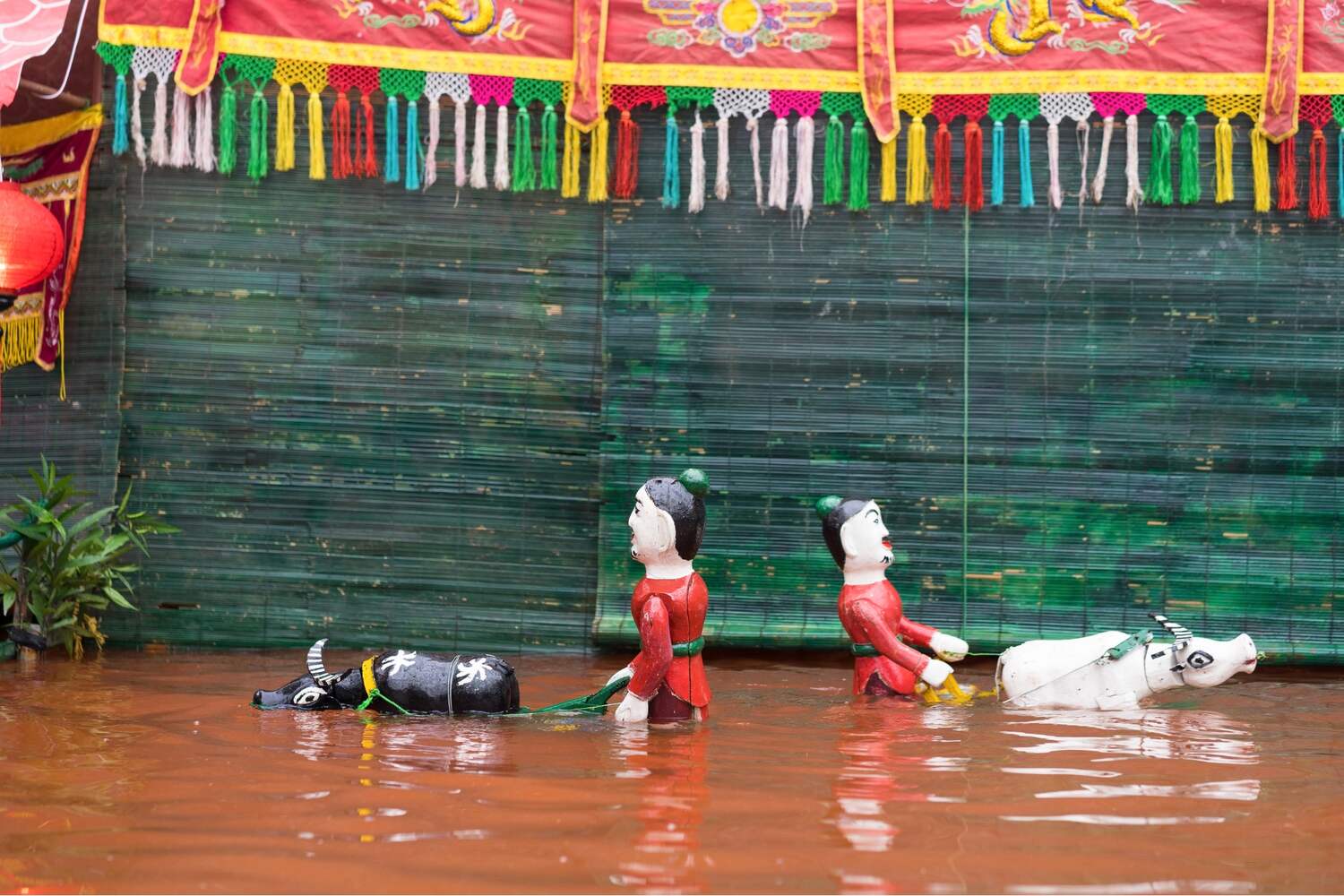 puppets playing in the water with wooden houses and greenery around